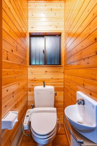a wooden bathroom with a toilet and a sink at 大人数で泊まれる宿一棟貸しkise-㐂瀬- in Amami