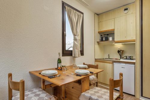 une cuisine avec une table en bois, des chaises et une fenêtre dans l'établissement Chamonix Sud - Bâtiment F 400 - Happy Rentals, à Chamonix-Mont-Blanc