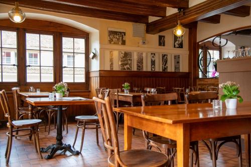 a restaurant with wooden tables and chairs and windows at Hotel de la Place in Vevey