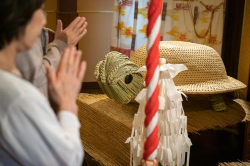 a person clapping in front of a hat and a pole at Futari Shizuka in Komagane