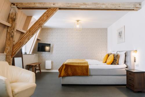 een slaapkamer met een bed, een bank en een stoel bij B&B Brasserie Villare in Wijlre