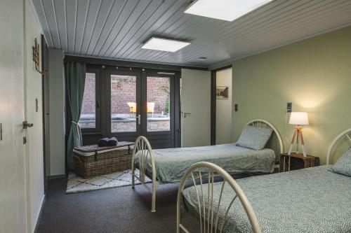 1 dormitorio con 2 camas y ventana en Vakantiewoning & Fietslogies V E L O, Tussen Hasselt en Maastricht, en Bilzen