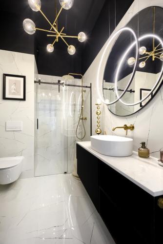 a bathroom with a sink and a shower and a mirror at AboutArtApartments - By the river in Wrocław
