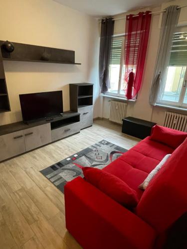 uma sala de estar com um sofá vermelho e uma televisão de ecrã plano em Accogliente Loft ben servito em Novara