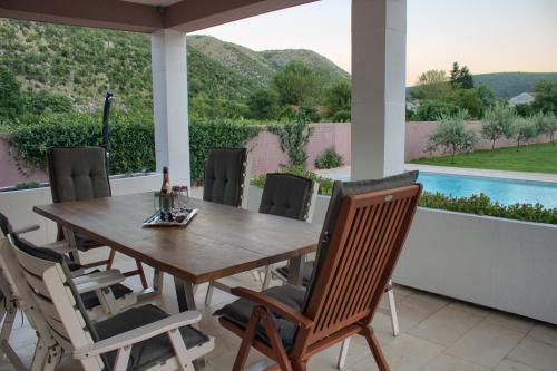 a wooden table and chairs on a patio with a pool at Villa Vita in Mostar