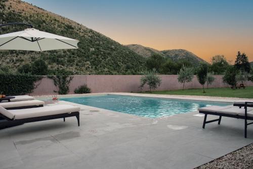 a swimming pool with an umbrella and two lounge chairs at Villa Vita in Mostar