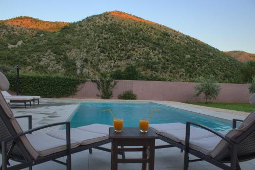 a pool with two glasses of orange juice on a table at Villa Vita in Mostar