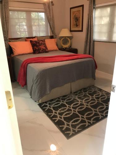 a bedroom with a bed with a red blanket and a rug at The Havens hideaway in Freeport