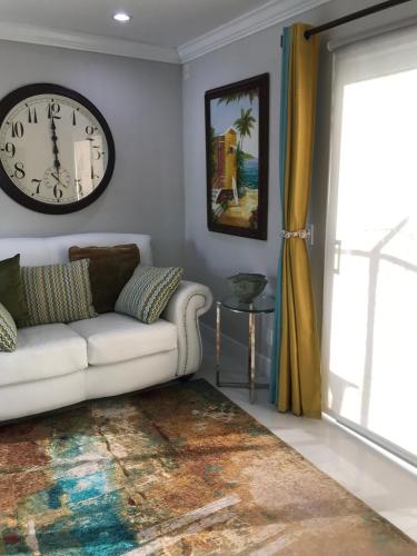 a living room with a white couch and a clock at The Havens hideaway in Freeport