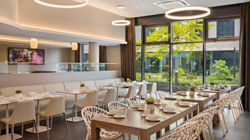 jadalnia ze stołami, krzesłami i oknami w obiekcie Hey Lou Hotel Monheim am Rhein w mieście Monheim am Rhein