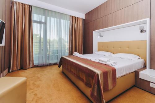 ママイアにあるHotel Scandinavia Mamaiaのベッドと大きな窓が備わるホテルルームです。