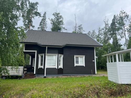 uma casa negra com um banco à frente. em Riihipeikko Jyväskylän läheisyydessä Muuramen Riihivuoressa em Muurame