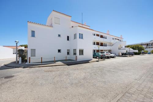 a white building with cars parked in a parking lot at Apartamento Navegador in Sagres