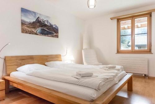 1 dormitorio con 1 cama grande con sábanas blancas en Apartment Alpin DG - GRIWA RENT AG, en Grindelwald