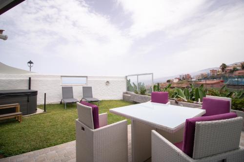 a patio with a white table and purple chairs at Casa Tulipanes & Spa in Santa Cruz de Tenerife