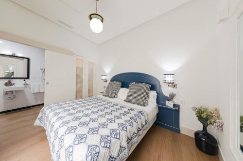 a bedroom with a blue and white bed and a bathroom at nüa cicerone in Seville