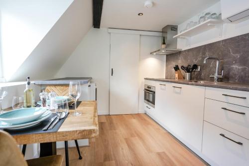 a kitchen with white cabinets and a wooden table at Beautiful Apartment With Loft in Delft
