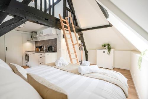 a bedroom with a large white bed and a kitchen at Beautiful Apartment With Loft in Delft