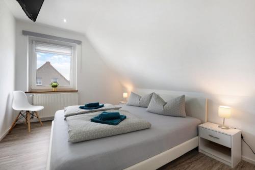 a white bedroom with a bed and a window at Haus Friede in Kalkhorst