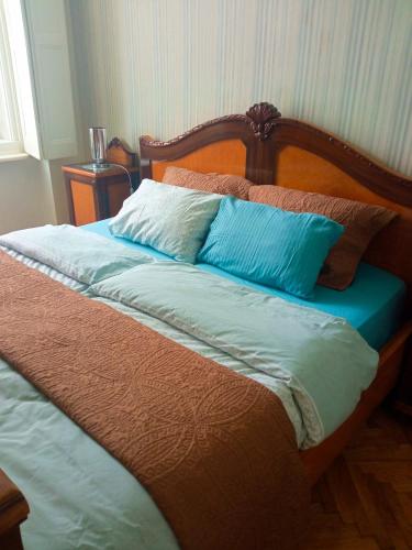 ein Bett mit blauen und weißen Kissen darauf in der Unterkunft Apartment DREAMS in Sombor