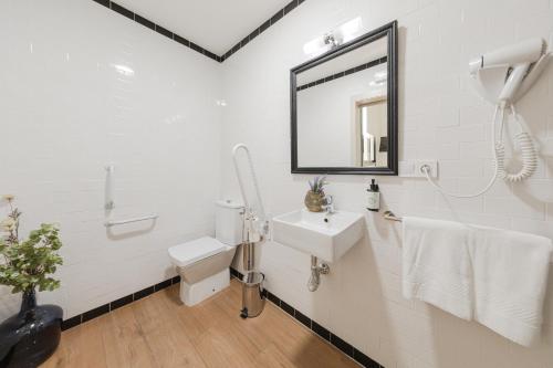 a white bathroom with a sink and a toilet at nüa cicerone in Seville