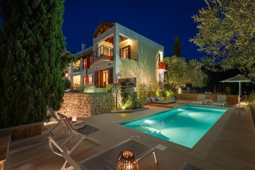 a villa with a swimming pool at night at Avista Villa in Vourvourou