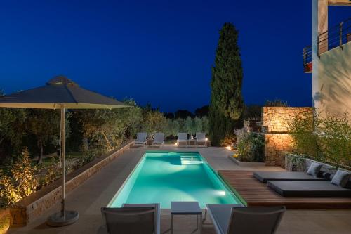 een zwembad met stoelen en een parasol bij Avista Villa in Vourvourou