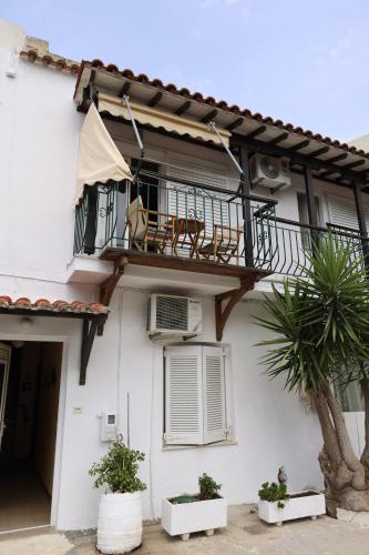 a white house with a balcony and a palm tree at Al Mar in Skiathos Town