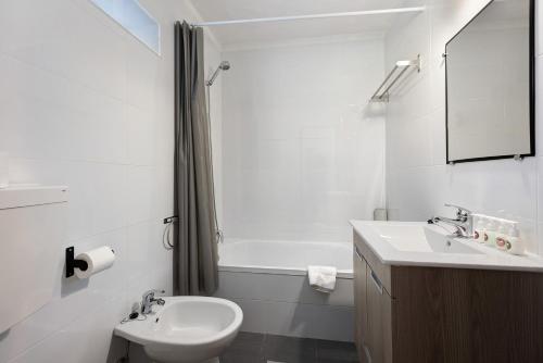 een badkamer met een wastafel, een toilet en een bad bij A Cerca - F in Lagos