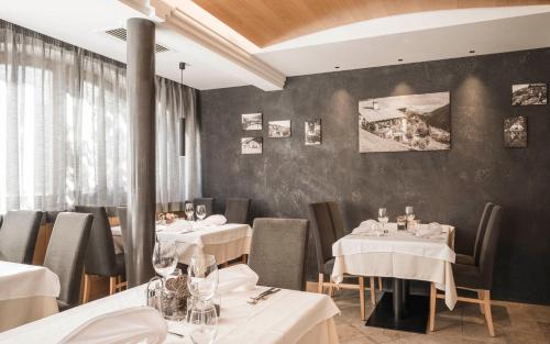 a restaurant with white tables and chairs and a wall at Hotel Alpenhof in Ultimo