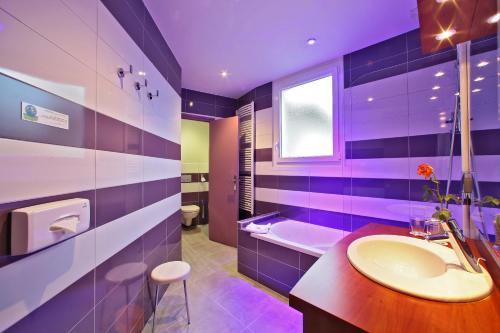 uma casa de banho roxa com um lavatório e uma banheira em The Originals City - Hôtel Saint-Martial, Limoges Centre em Limoges