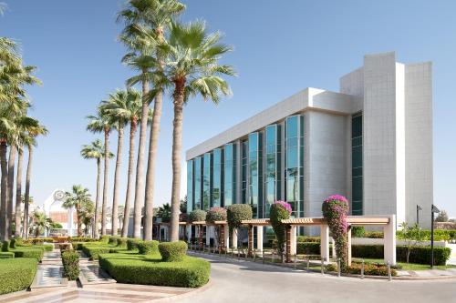 budynek z palmami przed nim w obiekcie Sheraton Jeddah Hotel w mieście Dżudda