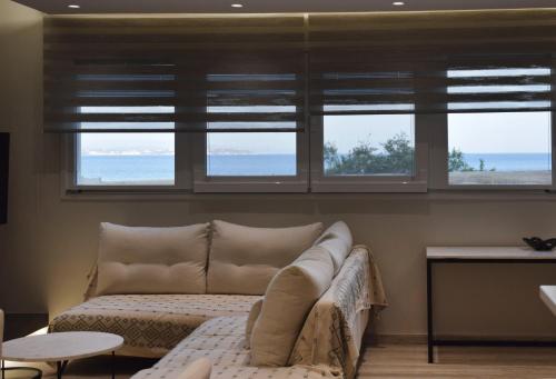 uma sala de estar com um sofá e três janelas em SeaView Apartment Megas Limnionas em Quios