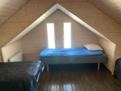 a bed in a wooden room with two windows at VILLA RIIHITONTTU MUURAME RIIHIVUORI in Muurame