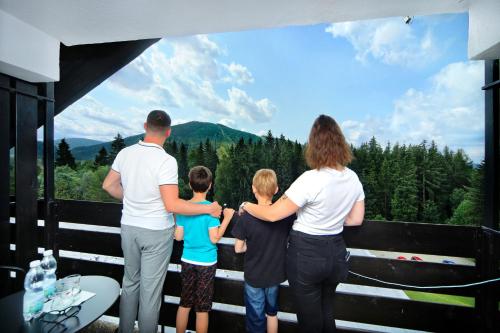 a family looking out of a window at the mountains at Wellness Hotel Svornost in Harrachov