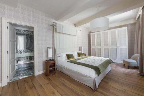 een witte slaapkamer met een bed en een stoel bij Palazzo Signoria luxury Apartments 7 - Perseo in Florence