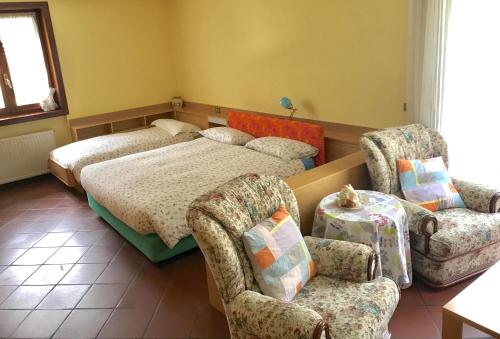 a bedroom with a bed and two chairs at B&B La Quercia in Dimaro