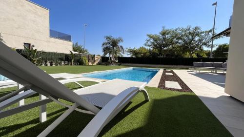 una piscina con un sillón junto a un patio en Villa with private heated pool - Roda Golf & Beach Resort, en San Javier