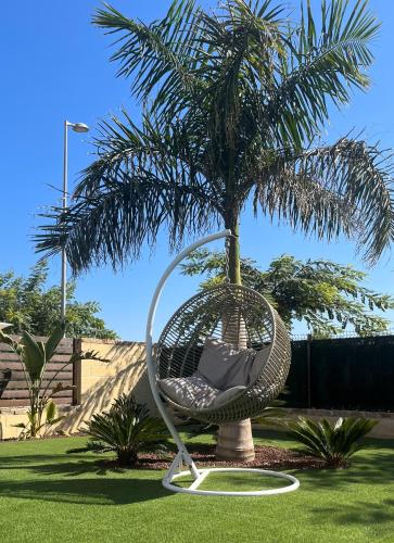 a swinging chair sitting in front of a palm tree at Villa with private heated pool - Roda Golf & Beach Resort in San Javier