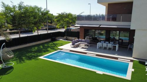 un patio trasero con piscina y césped verde en Villa with private heated pool - Roda Golf & Beach Resort, en San Javier