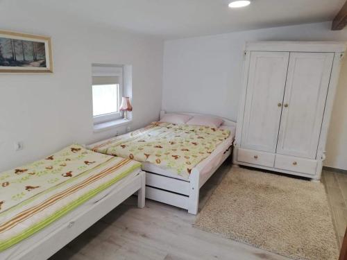 a bedroom with two beds and a cabinet at Domek Augustowski in Augustów