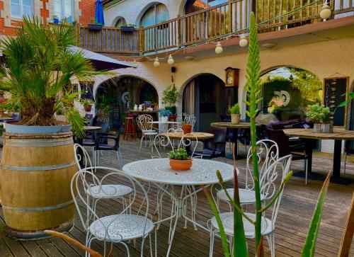 un patio extérieur avec des tables, des chaises et des plantes dans l'établissement L'Ecume des Jours, à Soulac-sur-Mer