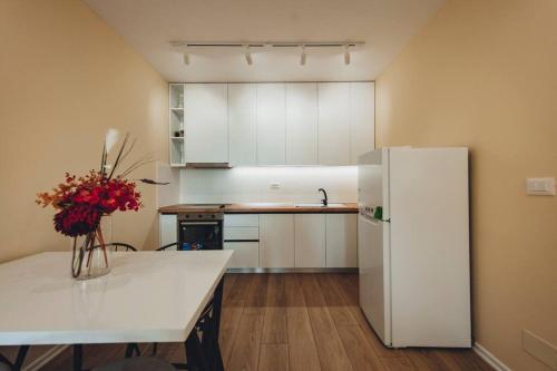 eine Küche mit einem weißen Kühlschrank und einem Tisch mit Blumen in der Unterkunft Luxury Apartment at Myslym Shyri in Tirana