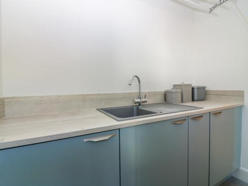 a kitchen with a sink and blue cabinets at Old Cooperage in Port Erroll