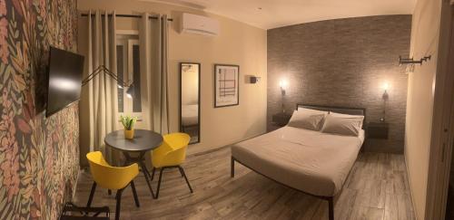 1 dormitorio con 1 cama, mesa y sillas amarillas en Kalasó Design Guest House, en Fiumicino