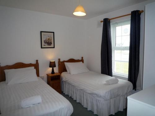 a bedroom with two beds and a window at Ballybunion Holiday Homes No 21 in Ballybunion