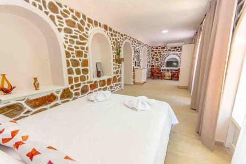 a bedroom with a white bed with a stone wall at VillaAnforaSelimiye in Selimiye