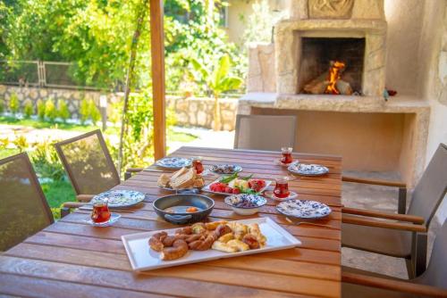 a wooden table with food on it with a fireplace at VillaAnforaSelimiye in Selimiye