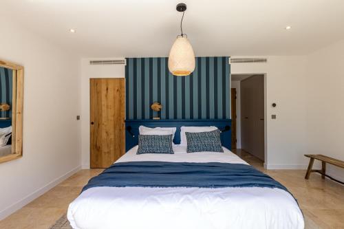 a bedroom with a blue and white bed with pillows at Le Refuge - Gigaro Lodges in La Croix-Valmer