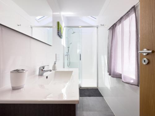 a white bathroom with a sink and a shower at Casa das Flores in Oliveira do Hospital